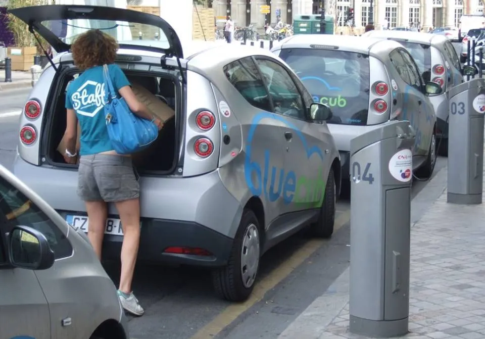 A BlueCar electric car-share vehicle parked and charging on a street in Bordeaux, France